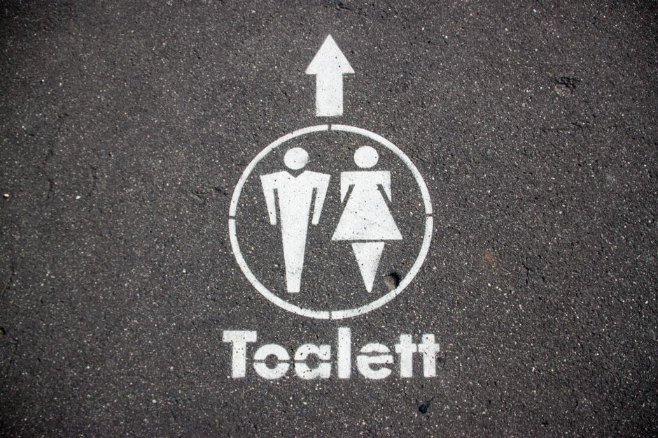アスファルト舗装で公衆トイレへの方向を示す道路標示。
