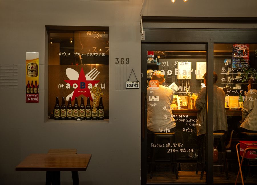 夜、ガラス扉越しに見える、店内の客で賑わう日本のバーの温かい雰囲気。