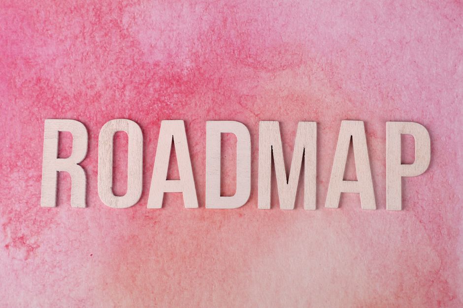 鮮やかなピンクの水彩画の背景に、「ROADMAP」と綴られた木製の文字。