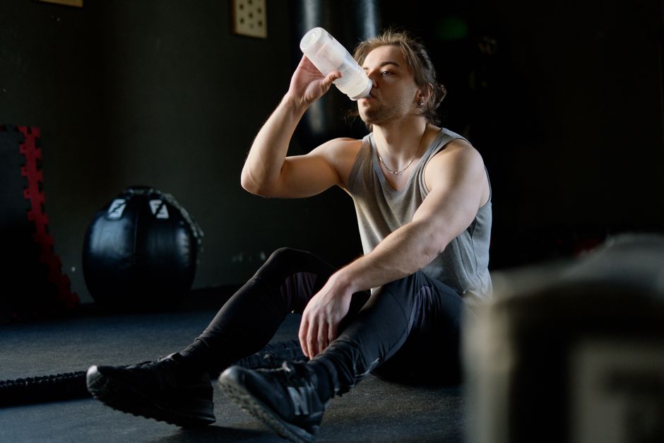 ジムで休憩を取り、トレーニング後に水を飲んで水分補給をしているアスリートの男性。