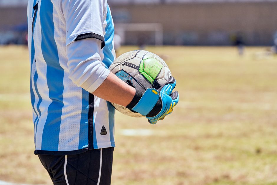 晴れた運動会で青と白のジャージを着てボールを持っているサッカー選手。