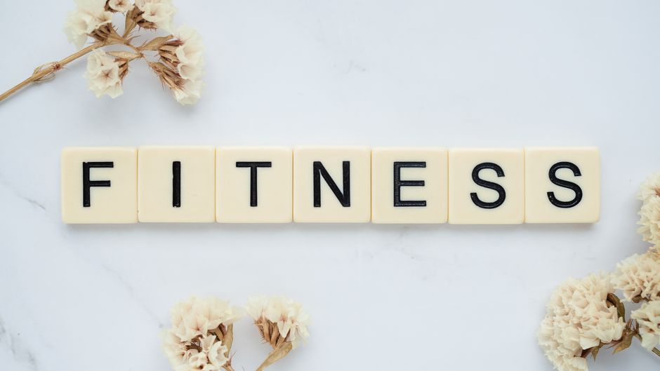 大理石の表面に白い花とともに『FITNESS』と綴られたスクラブルタイルのクローズアップ。